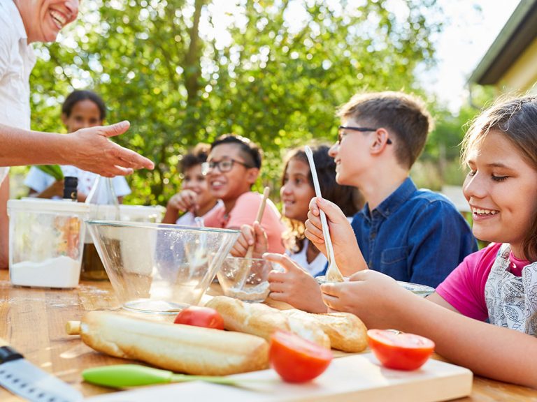 Children cooking and learning healthy recipes in a camp kitchen workshop at Kustermans
