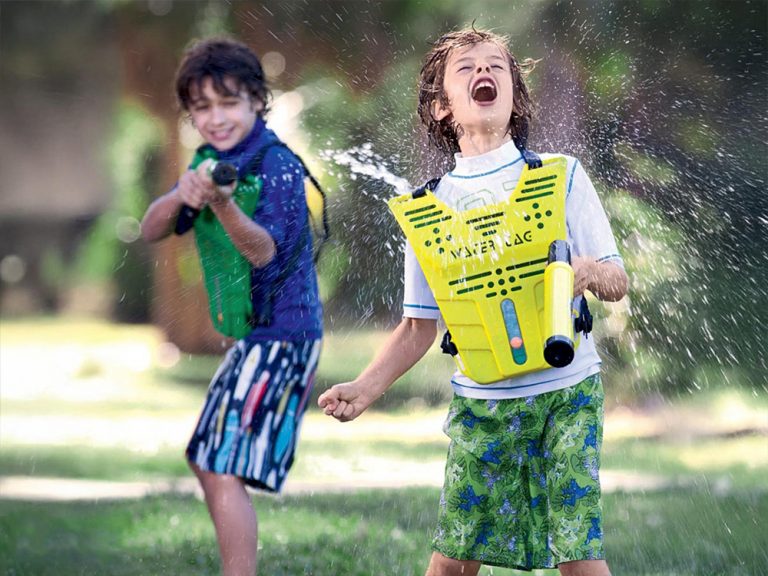 Campers running through water tag sprinklers at Kustermans Summer Camp