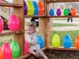 Toddler posing among colourful oversized Easter eggs at a farm photo station