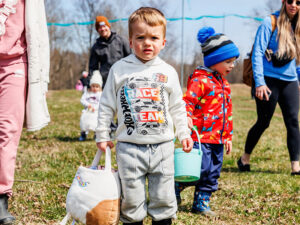 Two young boys carrying Easter egg hunt baskets at an outdoor farm event