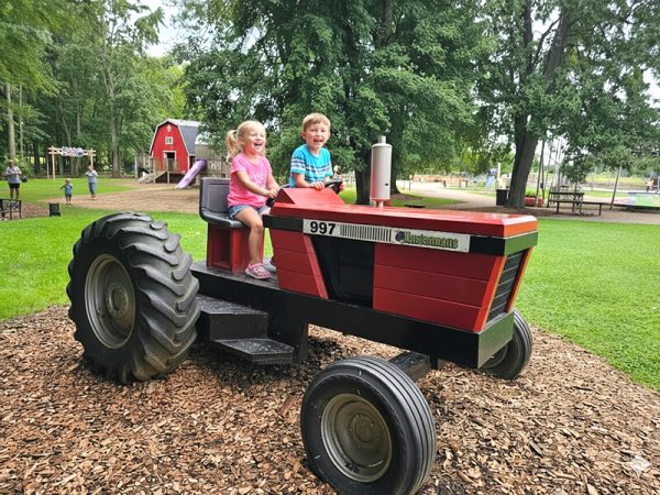 Young child sitting in the seat of a play tractor at Kustermans Farm